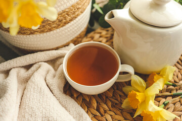 Cup of tea, candles, basket with daffodils, spring aesthetic photo