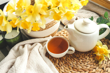Obraz na płótnie Canvas Cup of tea, candles, basket with daffodils, spring aesthetic photo