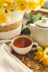 Cup of tea, candles, basket with daffodils, spring aesthetic photo