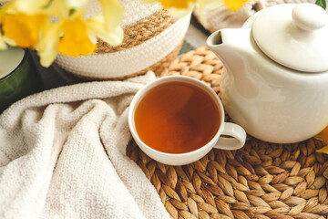 Cup of tea, candles, basket with daffodils, spring aesthetic photo