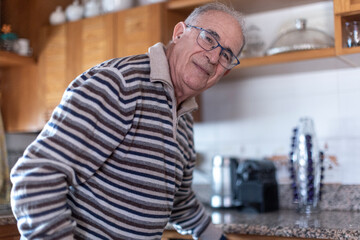 signore anziano con maglia a righe è indaffarato nella sua cucina