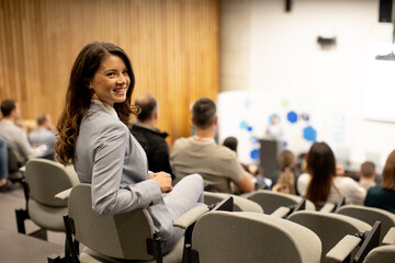 Young woman sitting in audience on conference or workshop