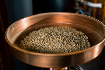 Fresh coffee beans lie in the chamber of the coffee machine before roasting for the production of fragrant coffee