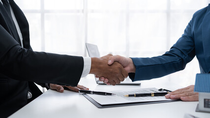 Real estate agent shakes hands with a client to sign a home purchase contract congratulating the client on the purchase. - obrazy, fototapety, plakaty