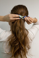 Fototapeta premium Young woman clipping her blond hair with a snap hair clip