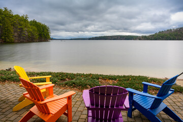 Photograph of Squam Lake in New Hampshire with Adirondack  chairs in the foreground.