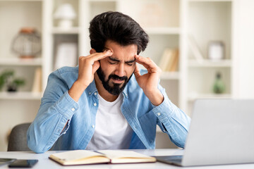 Tired Young Indian Freelancer Guy Having Headache While Working In Home Office