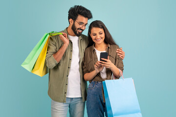 Loving indian couple using nice shopping mobile app, copy space