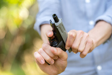 Anonymous unrecognizable man reloading cocking a small plastic toy gun, fake pistol, shooter...