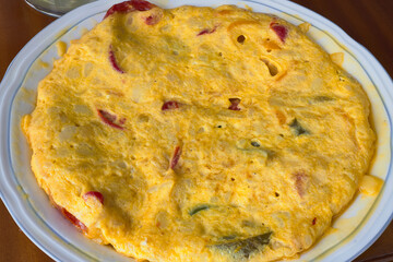 Dish with hortelana potato omelette. This tortilla is made with potato, red pepper, green pepper, yellow pepper and onion.