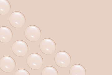 Drops of transparent gel or water in rows. On a beige background.