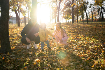 Happy family father mother and child son has fun on a walk in the autumn leaf fall in park