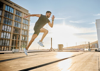 I dont hit the gym regularly but I workout everyday. Shot of a sporty young man out on a rooftop for a workout.