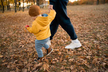 Cute little child boy with his father walk on a background of beautiful autumn forest. Dad and son outdoor in fall season time together.