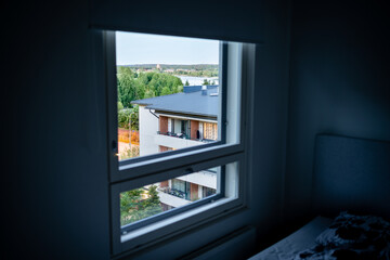 Window in apartment. Condo building house outside, neighbor. Dark room. Rental housing or real estate property. Street in residential area and neighborhood. Student flat or family home. Summer night.