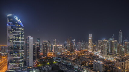 Naklejka premium Panorama showing Dubai's business bay towers aerial night timelapse. Rooftop view of some skyscrapers