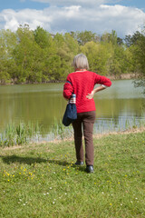 Fototapeta na wymiar Femme un sac à l'épaule promenant dans un parc d'Agen au bord d'un lac