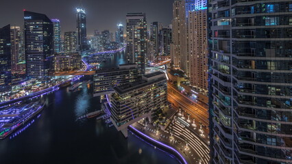Obraz na płótnie Canvas Aerial view to Dubai marina skyscrapers around canal with floating boats night timelapse