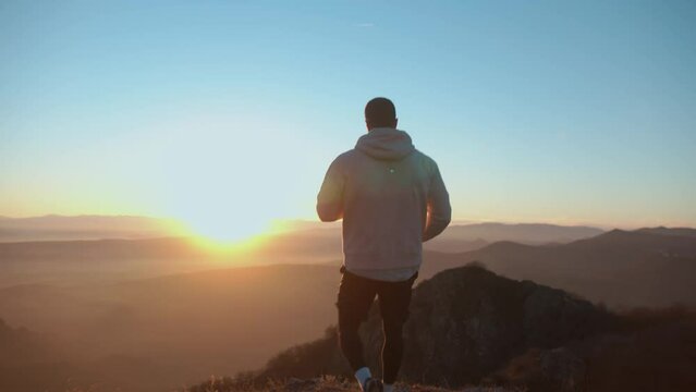 Young muscular man running through the beautiful landscape at sunset . 