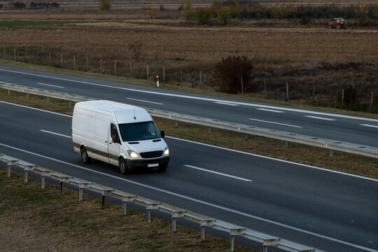 White delivery van on the highway. White modern delivery small shipment cargo courier van moving fast on motorway road to city urban suburb. The business distribution and logistics express service.