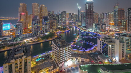 Fototapeta premium Dubai Marina with several boat and yachts parked in harbor and skyscrapers around canal aerial day to night timelapse.