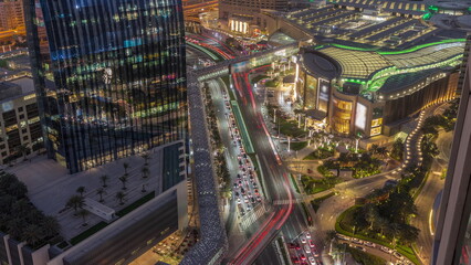Aerial panorama of Downtown Dubai with shopping mall and traffic on a street day to night timelapse from above, UAE