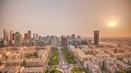 Obraz premium Sunrise over skyscrapers in Barsha Heights district and low rise buildings in Greens district aerial timelapse.