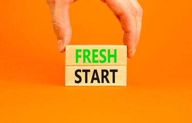 Fresh start and motivational symbol. Concept words Fresh start on beautiful wooden block. Beautiful orange background. Businessman hand. Business motivational Fresh start concept. Copy space.