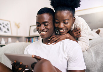 What are you watching. Shot of a young couple using a digital tablet together at home.