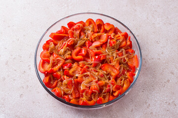 Glass form with stewed chopped red sweet pepper, onion, thyme and honey on a beige textured background, top view. Stage of cooking delicious red pepper tart or other vegetable dish - Powered by Adobe