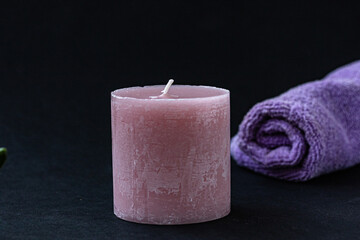 Obraz na płótnie Canvas A pink candle and a soft purple towel isolated on background. Spa concept. Copy space to design key visual layout