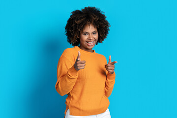 Cute young black woman pointing at camera on blue
