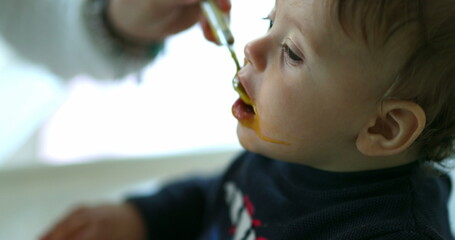 Parent feeding baby blond boy son