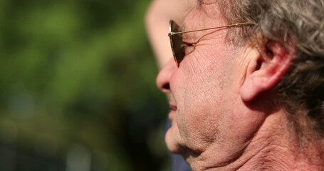Fototapeta premium Older man wearing sunglasses outside in the sunlight resting. Senior retired face in outdoors