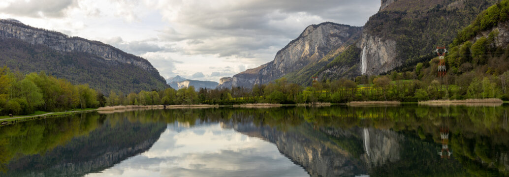 image panoramique montrant un magnifique lac de montagne ensoleillé et une belle cascade. Lac des Ilettes en Haute Savoie