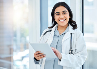 Doing her rounds with her digital assistant. Portrait of a young doctor using a digital tablet in a hospital.