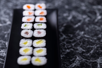 set of sushi rolls with seafood on a black stone background