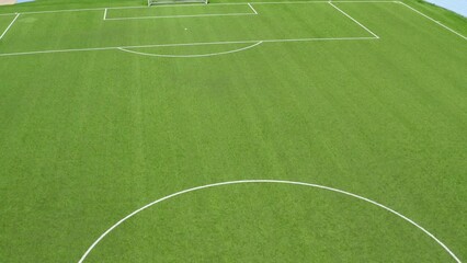 Aerial closeup of the penalty area and midfield circle on an empty synthetic grass soccer field. Here a penalty is taken in a soccer game. - Powered by Adobe