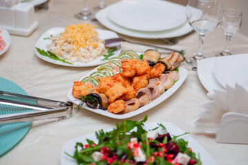 Table setting for the holiday. Round table with salads and sliced rolls, appetizers, bread.