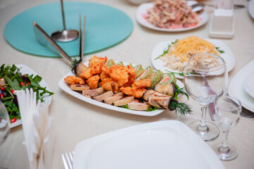 Table setting for the holiday. Round table with salads and sliced rolls, appetizers, bread.