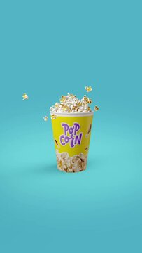 A bucket of sweet and airy popcorn, spectacularly filled on a blue background. Vertical Slow Motion Footage
