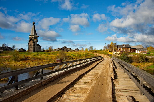 Saminsky churchyard. Russia. 05 October 2018. View of the wooden bridge over the Samina River near the ancient wooden Orthodox Church of Elijah the Prophet in a picturesque place of the Vologda region