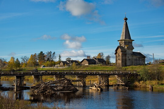 Saminsky churchyard. Russia. 05 October 2018. View of the wooden bridge over the Samina River near the ancient wooden Orthodox Church of Elijah the Prophet in a picturesque place of the Vologda region