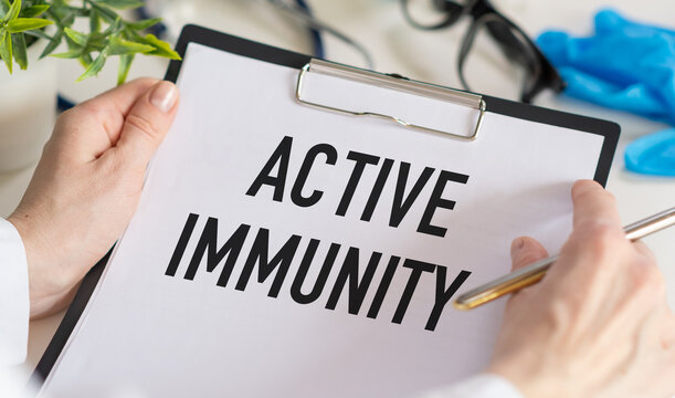 Text Active Immunity on a notebook in the hands of a doctor against the background of a table with medicaments. Medical concept photo