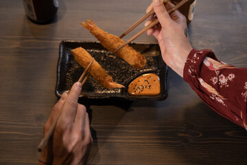 detail of the hands of the bride and groom eat pango shrimp and hold the food with chopsticks