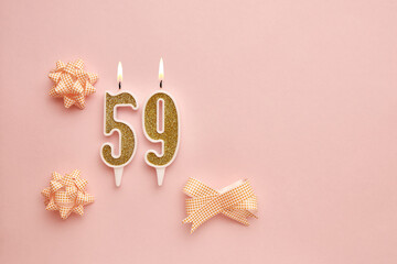 Candles with the number 59 on a pastel pink background with festive decor. Happy birthday candles. The concept of celebrating a birthday, anniversary, important date, holiday. Copy space. banner