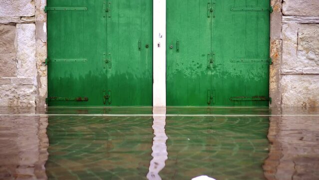 Wide dark green painted gates reflect in high flood water