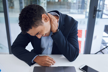 Stressed out and feeling it. Shot of a young businessman experiencing neck pain while working in an office.