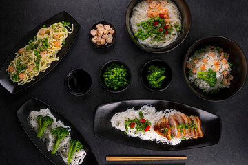 Various dishes of Asian cuisine with different types noodles and rice with shrimp, duck, vegetables and black sesame