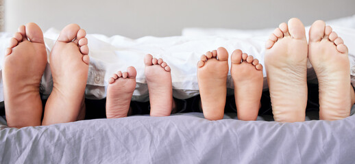 Feet of family lying in bed. Closeup of feet of parents and children in bed. Family relaxing in bed...